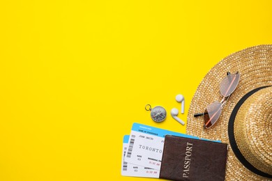 Flat lay composition with passport, tickets and travel items on yellow background. Space for text