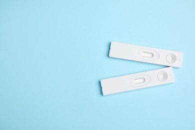 Two disposable express hepatitis tests on light blue background, flat lay. Space for text