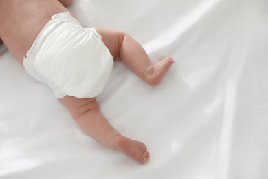Photo of Cute little baby in diaper on bed, top view