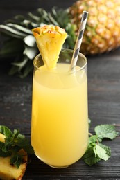 Photo of Delicious fresh pineapple juice on black wooden table, closeup