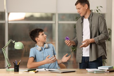 Father talking with his teenage son about contraception while he doing homework at home. Sex education concept