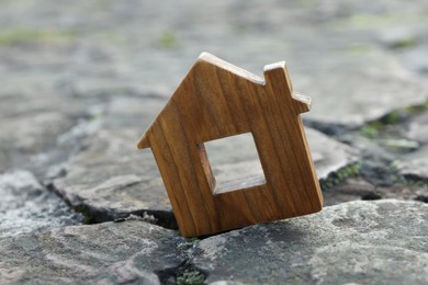Photo of Wooden house model between cracks on stone road. Earthquake disaster