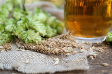 Photo of Beer, fresh hops and ears of wheat on wooden table, closeup