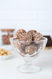Photo of Glass dessert bowl of tasty chocolate balls on white table, closeup