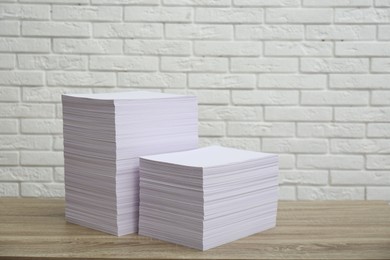 Photo of Stacks of paper sheets on wooden table. Space for text