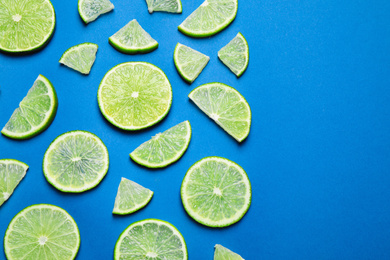 Juicy fresh lime slices on blue background, flat lay. Space for text