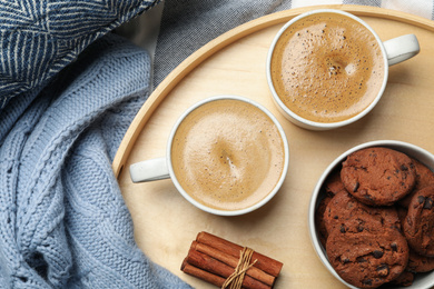 Cups of delicious hot coffee and cookies on fabric, flat lay. Winter drink