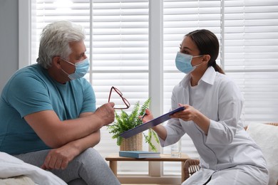 Photo of Doctor working with senior man in protective mask at nursing home