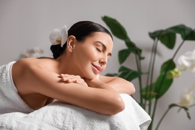 Photo of Beautiful happy woman relaxing on massage table in spa salon