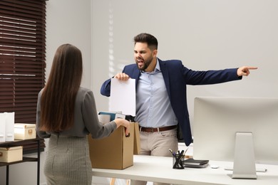 Boss dismissing young woman from work in office