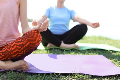 Group of women practicing yoga outdoors on sunny day