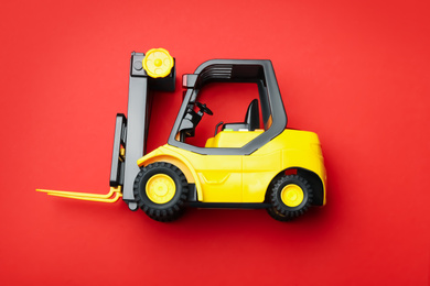 Top view of toy forklift on red background. Logistics and wholesale concept