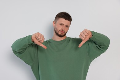 Young man showing thumbs down on white background