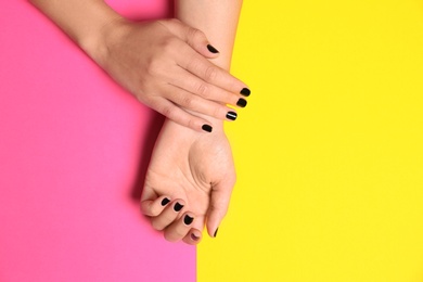 Woman showing black manicure on color background, top view with space for text. Nail polish trends