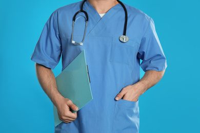 Doctor with clipboard on blue background, closeup