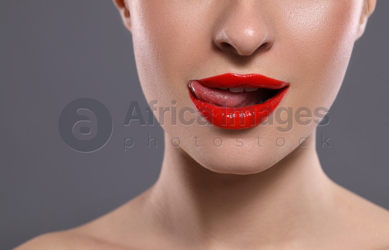 Young woman with red lips makeup on grey background, closeup. Space for text