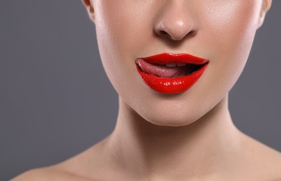 Photo of Young woman with red lips makeup on grey background, closeup. Space for text