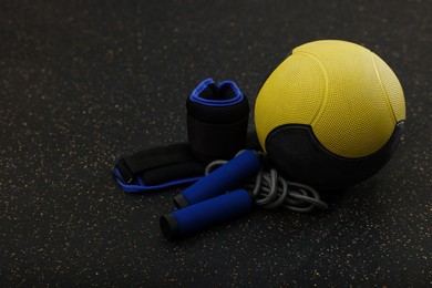 Yellow medicine ball, weighting agents and skipping rope on floor, space for text