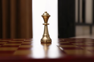 Golden Queen chess piece on board indoors