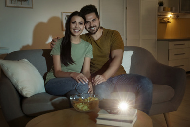 Young couple watching movie using video projector at home