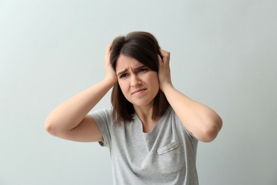 Young woman suffering from migraine on white background