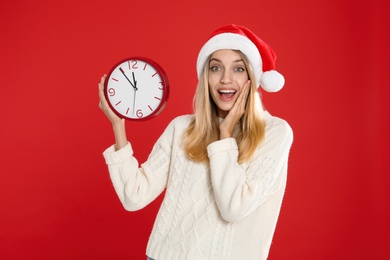 Woman in Santa hat with clock on red background. New Year countdown