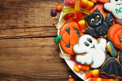 Tasty cookies and sweets for Halloween party on wooden table, top view. Space for text