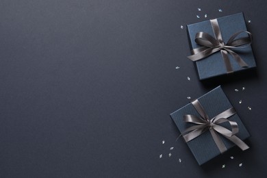 Beautiful gift boxes and confetti on black background, flat lay. Space for text