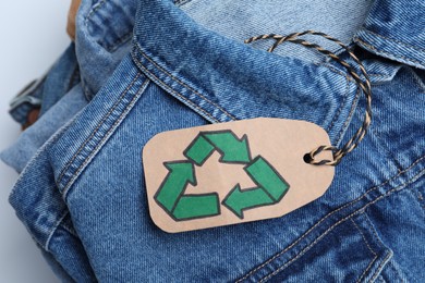 Photo of Stack of clothes with recycling label on white background, closeup