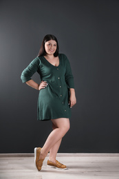 Beautiful overweight woman posing near black wall. Plus size model
