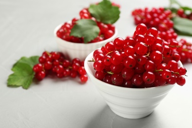 Delicious red currants in bowl on light table. Space for text