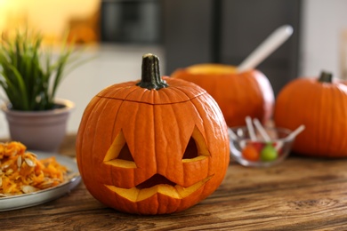Pumpkin jack o'lantern on wooden table indoors. Halloween celebration