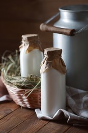 Tasty fresh milk in can and bottles on wooden table