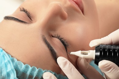 Photo of Young woman undergoing procedure of permanent eyeliner makeup, closeup