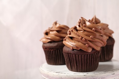 Photo of Delicious chocolate cupcakes with cream and beads on white table, closeup