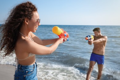 Couple with water guns having fun on beach