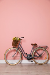 Retro bicycle with wicker basket near color wall
