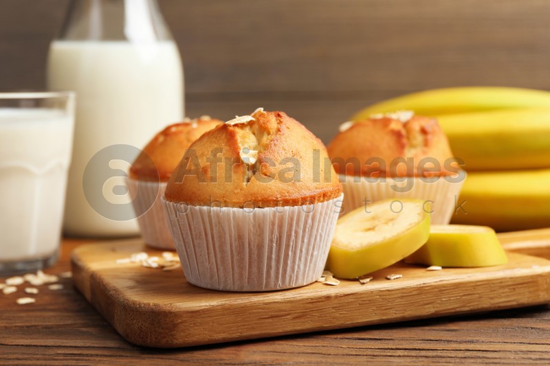 Photo of Tasty muffins served with banana on wooden table