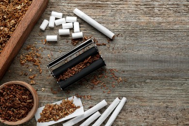 Photo of Flat lay composition with roller and tobacco on old wooden table, space for text. Making hand rolled cigarettes