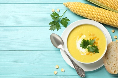 Delicious creamy corn soup served on turquoise wooden table, flat lay. Space for text