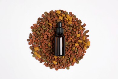 Glass bottle of tincture and dry pet food on white background, top view