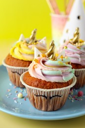 Cute sweet unicorn cupcakes and party items on yellow background, closeup