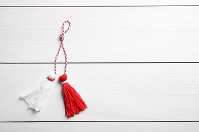 Photo of Traditional martisor on white wooden background, top view with space for text. Beginning of spring celebration