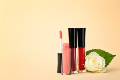 Lip glosses and flower on color background