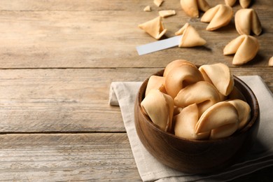 Photo of Tasty fortune cookies with prediction on wooden table, space for text