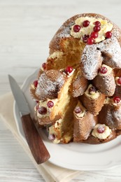 Photo of Delicious Pandoro Christmas tree cake with powdered sugar and berries on white wooden table, closeup