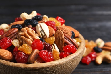 Bowl with different dried fruits and nuts on table, closeup