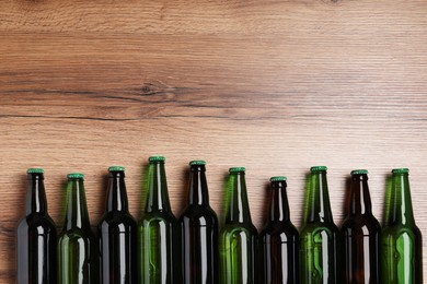 Photo of Bottles of tasty beer on wooden table, flat lay. Space for text