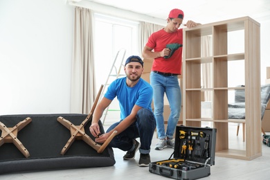Male movers assembling furniture in new house