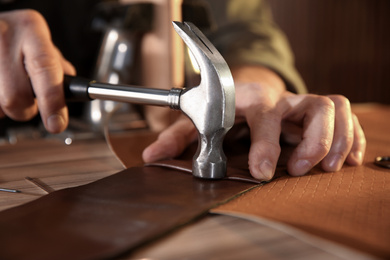 Man working with piece of leather at table, closeup